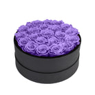 Black round box filled with purple roses on a white background