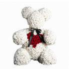 Teddy bear made of white roses with a red heart and black ribbon on a white background