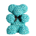 Turquoise rose teddy bear with a black bow on a white background