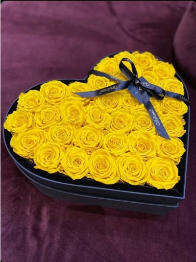 Heart-shaped box filled with yellow roses on a purple background