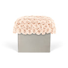 Floral arrangement with pink roses on a gray box against a white background