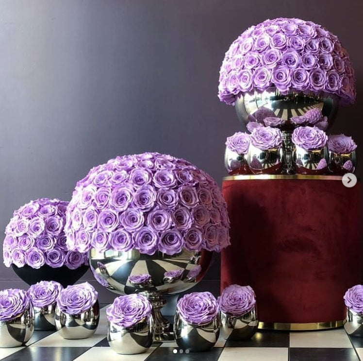 Decorative arrangement of purple flowers in various containers on a checkered surface.