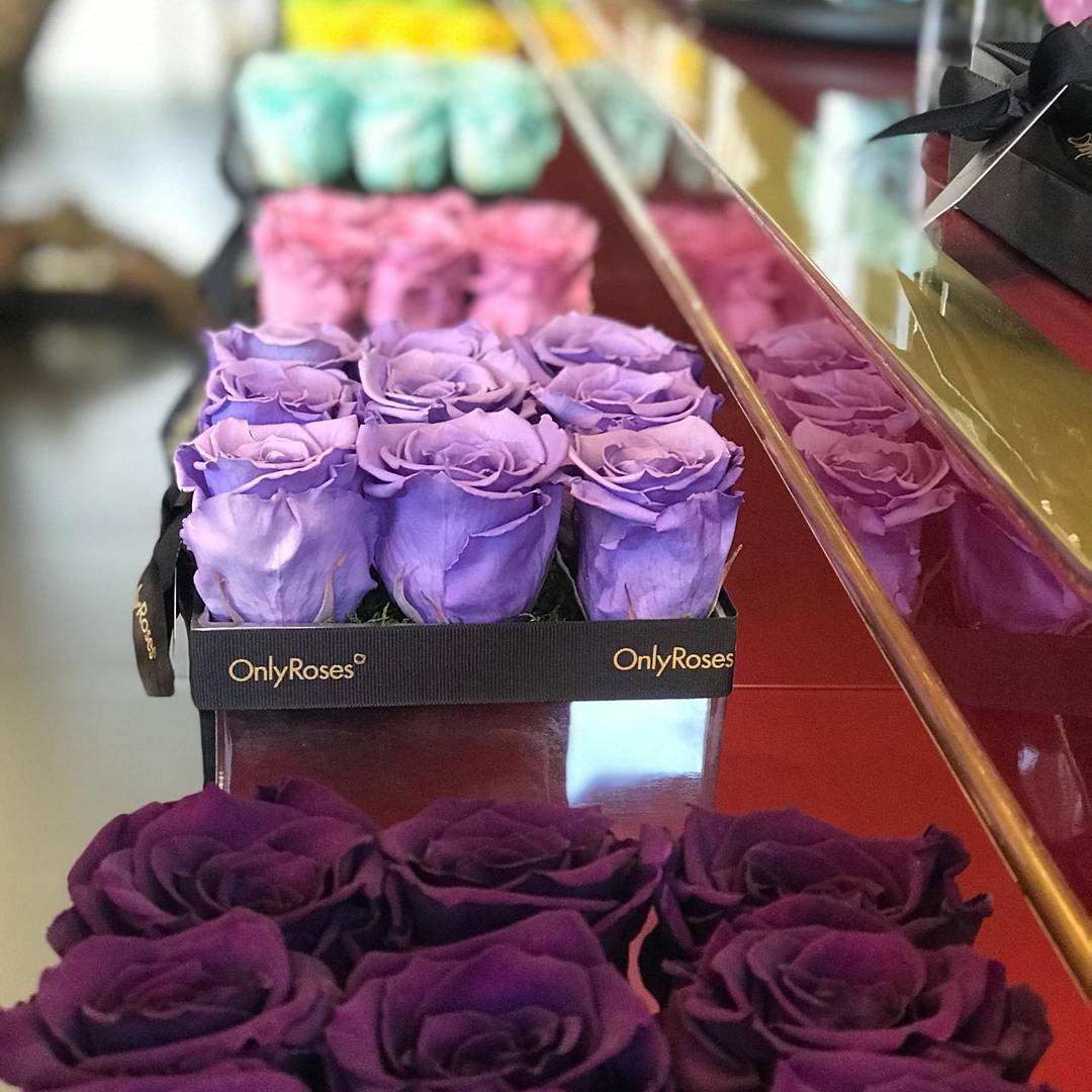 Purple roses in a box with 'OnlyRoses' branding on a reflective surface.