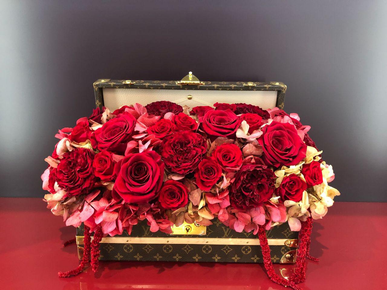 Decorative box filled with red and pink roses on a dark background