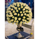 Large bouquet of white roses in a decorative vase on a cart.