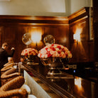 Decorative floral arrangements on a bar counter with wooden paneling in the background. Chamagne Bowls
