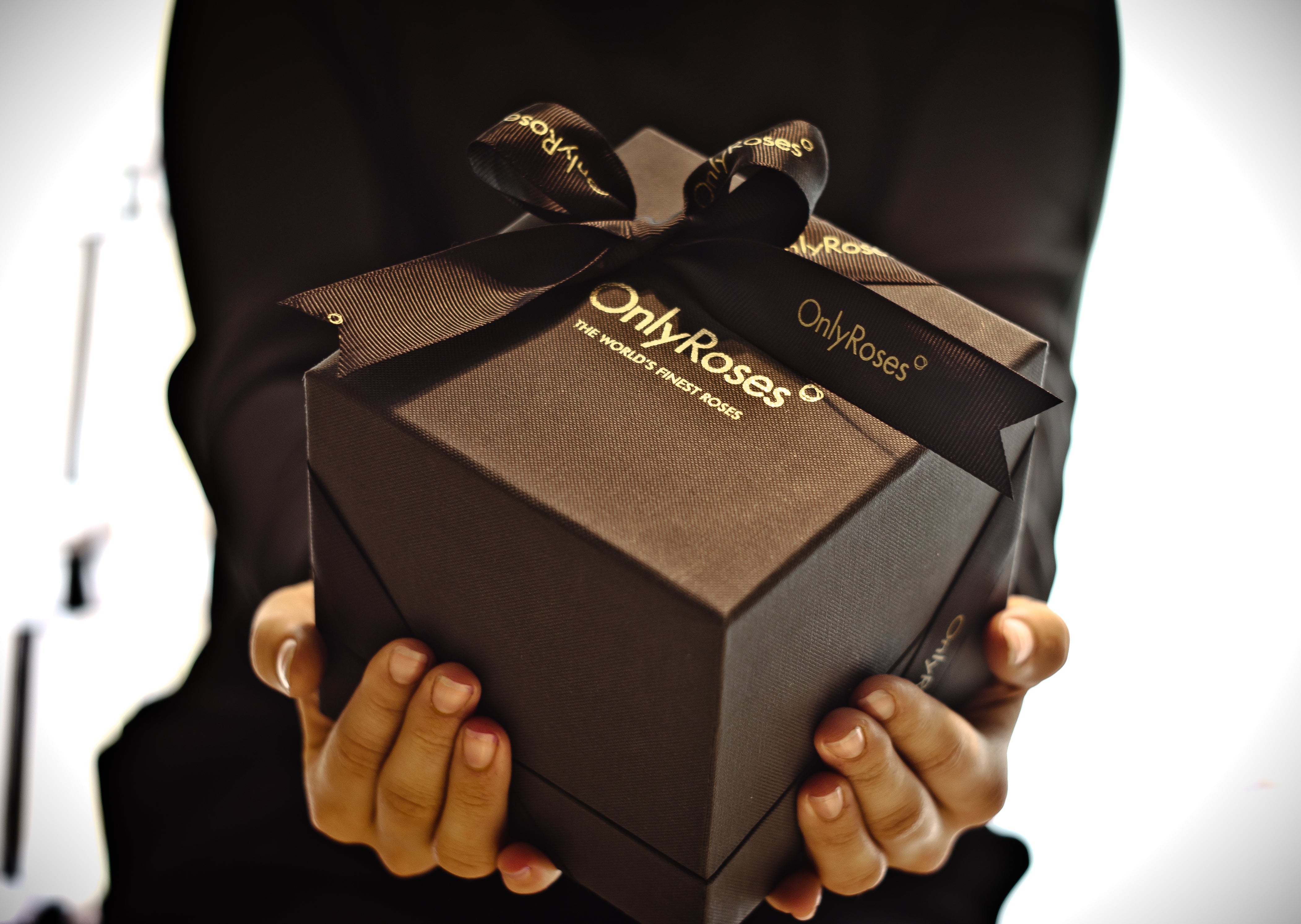 Person holding a brown gift box with 'Only Roses' branding.