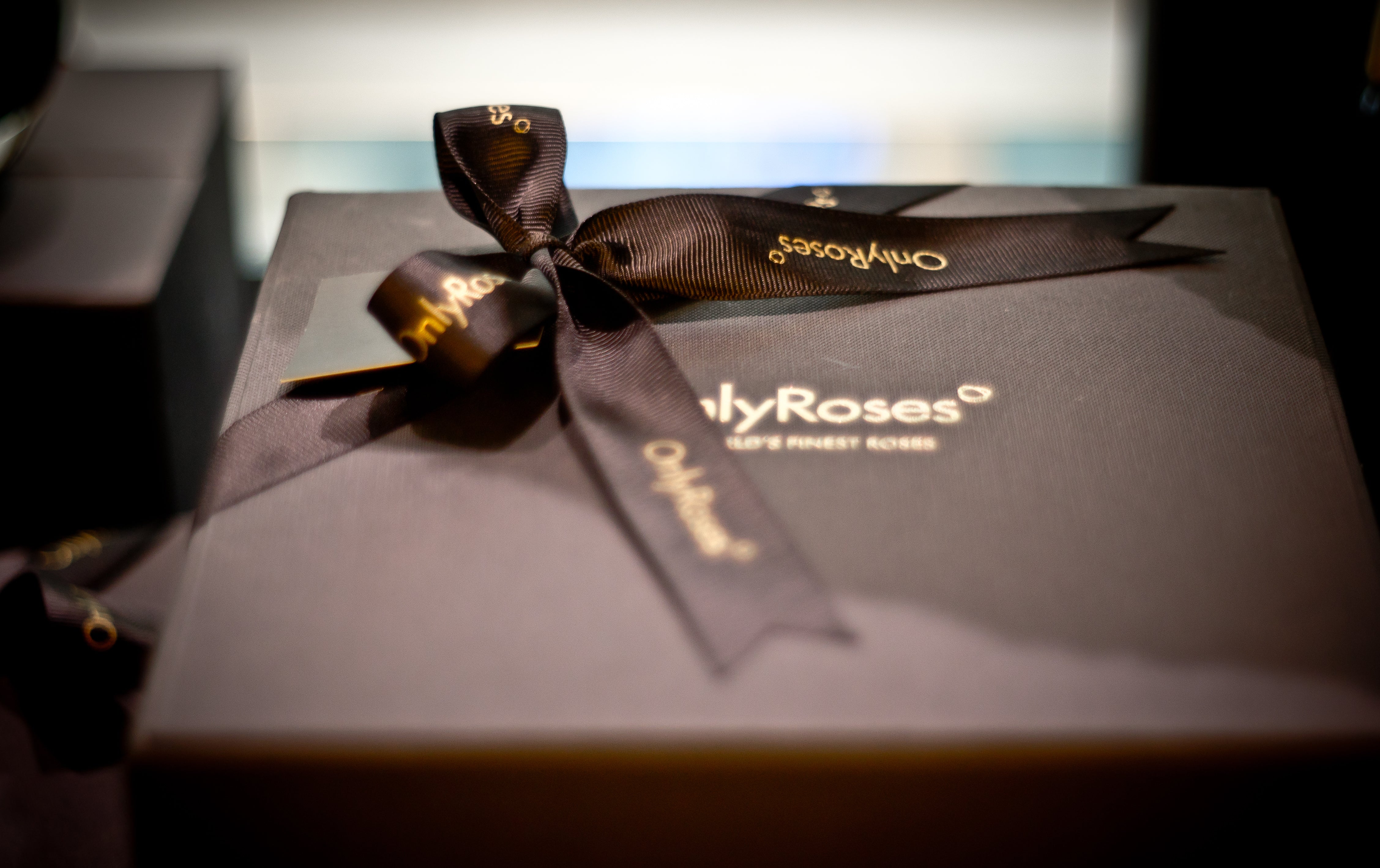 Gift box with a bow featuring 'Only Roses' branding on a blurred background