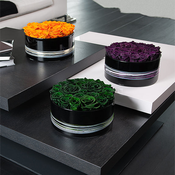 Three round black boxes with colorful roses on a modern interior setting