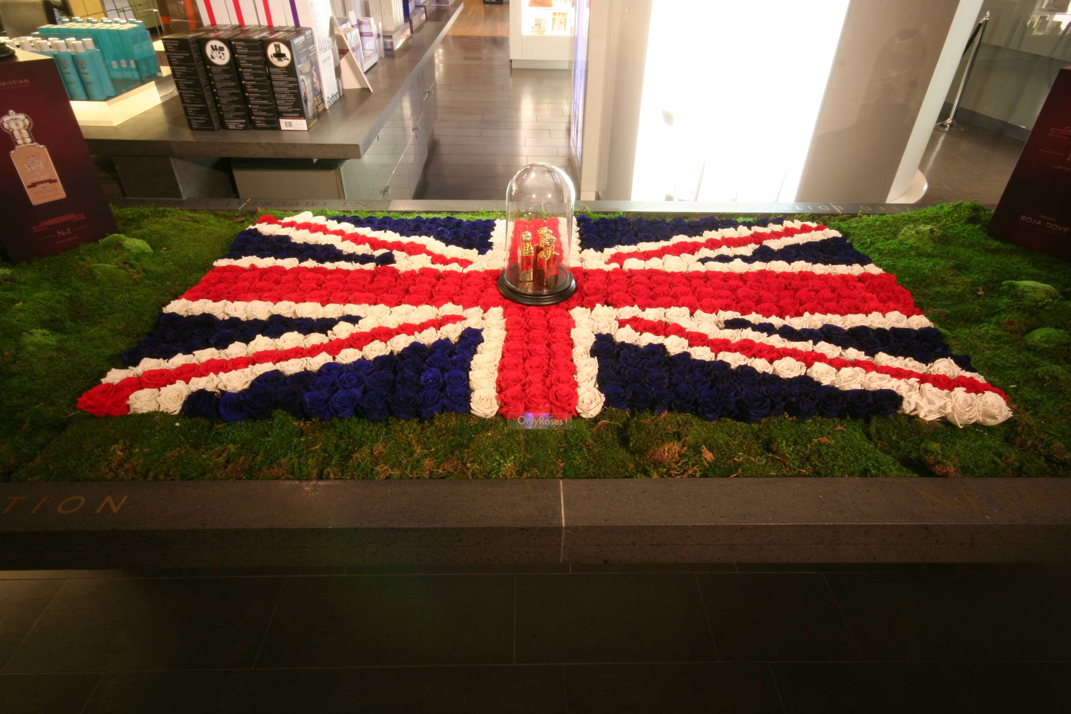 Union Jack flag made of flowers on a grass-like surface indoors