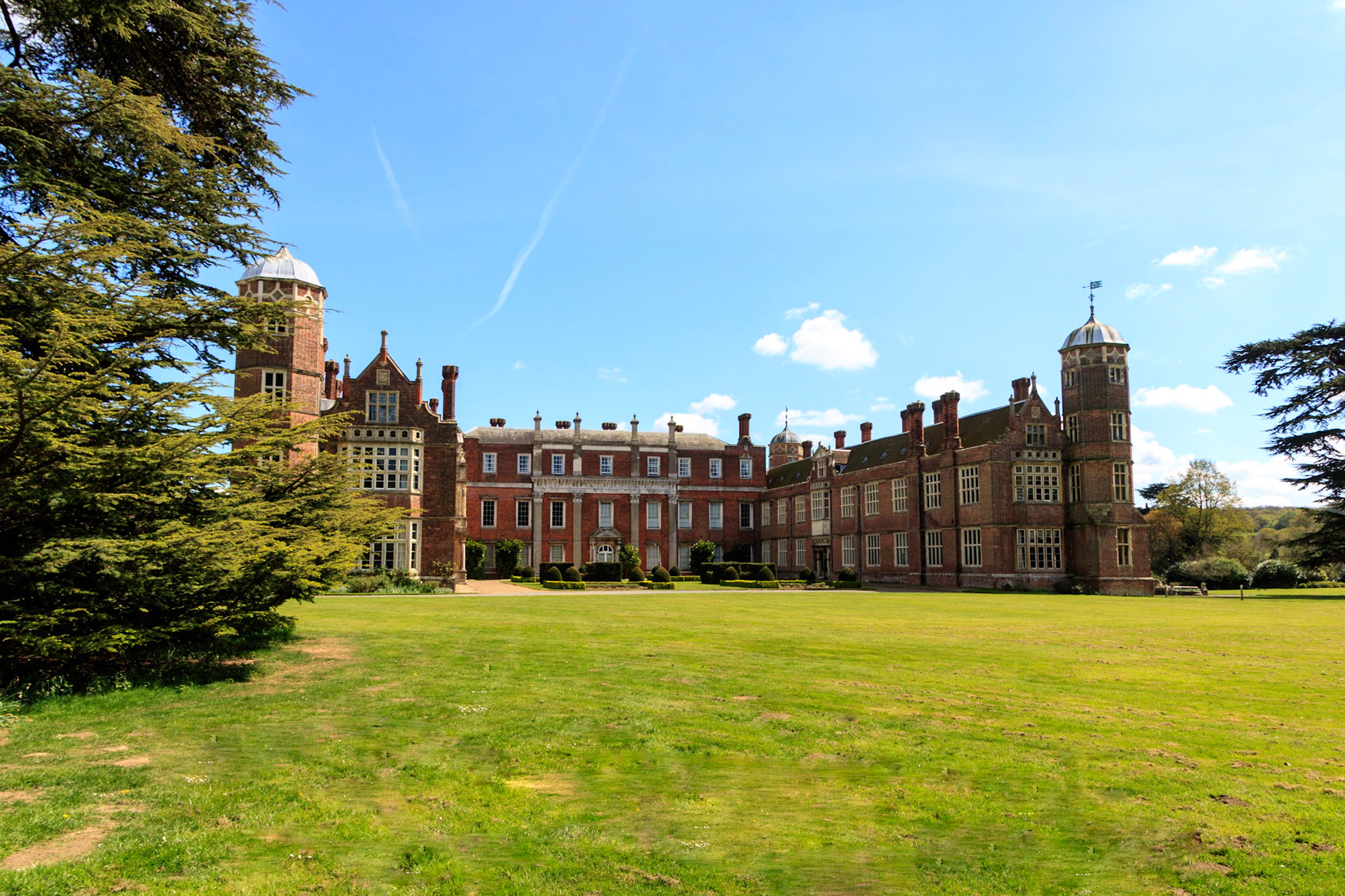 Large historic mansion with a clear blue sky and green grass