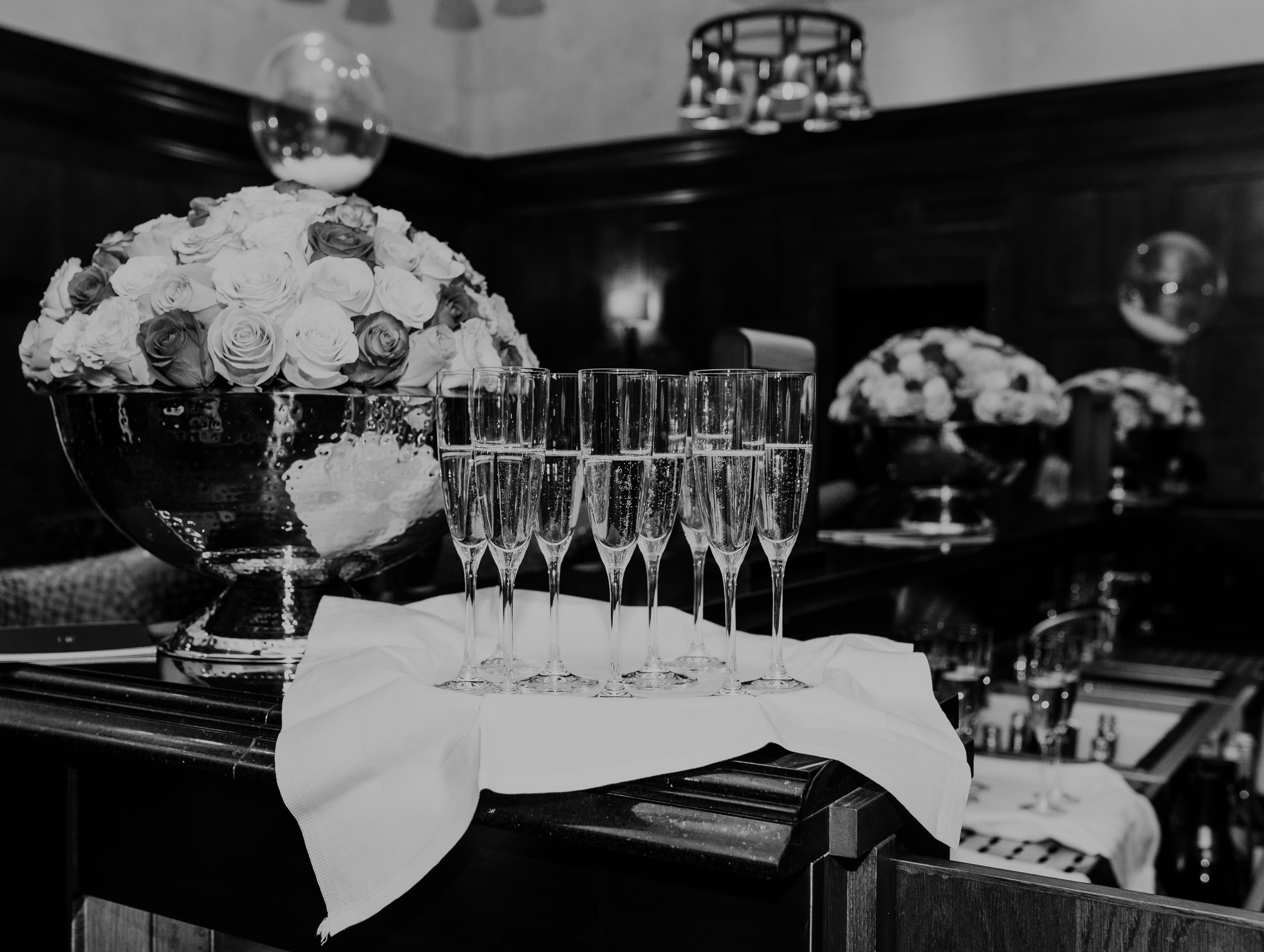 Set of champagne glasses on a tray with floral arrangements in the background