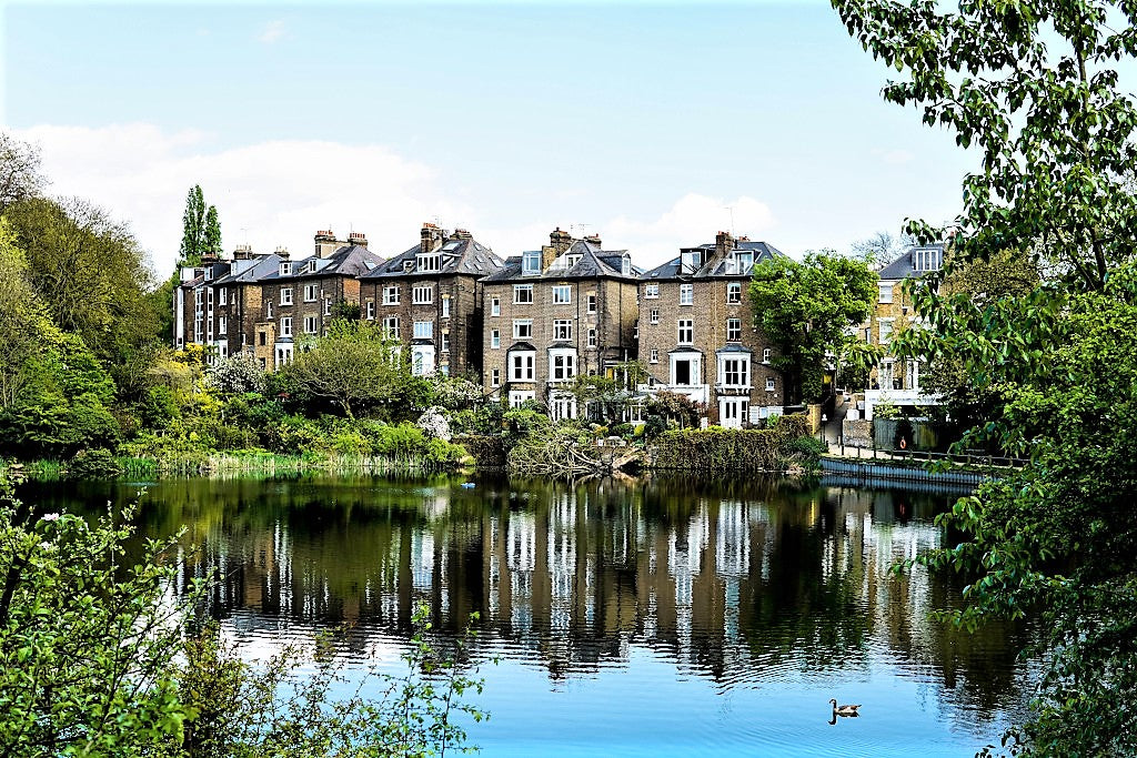 Stately home with a pond and trees in the foreground