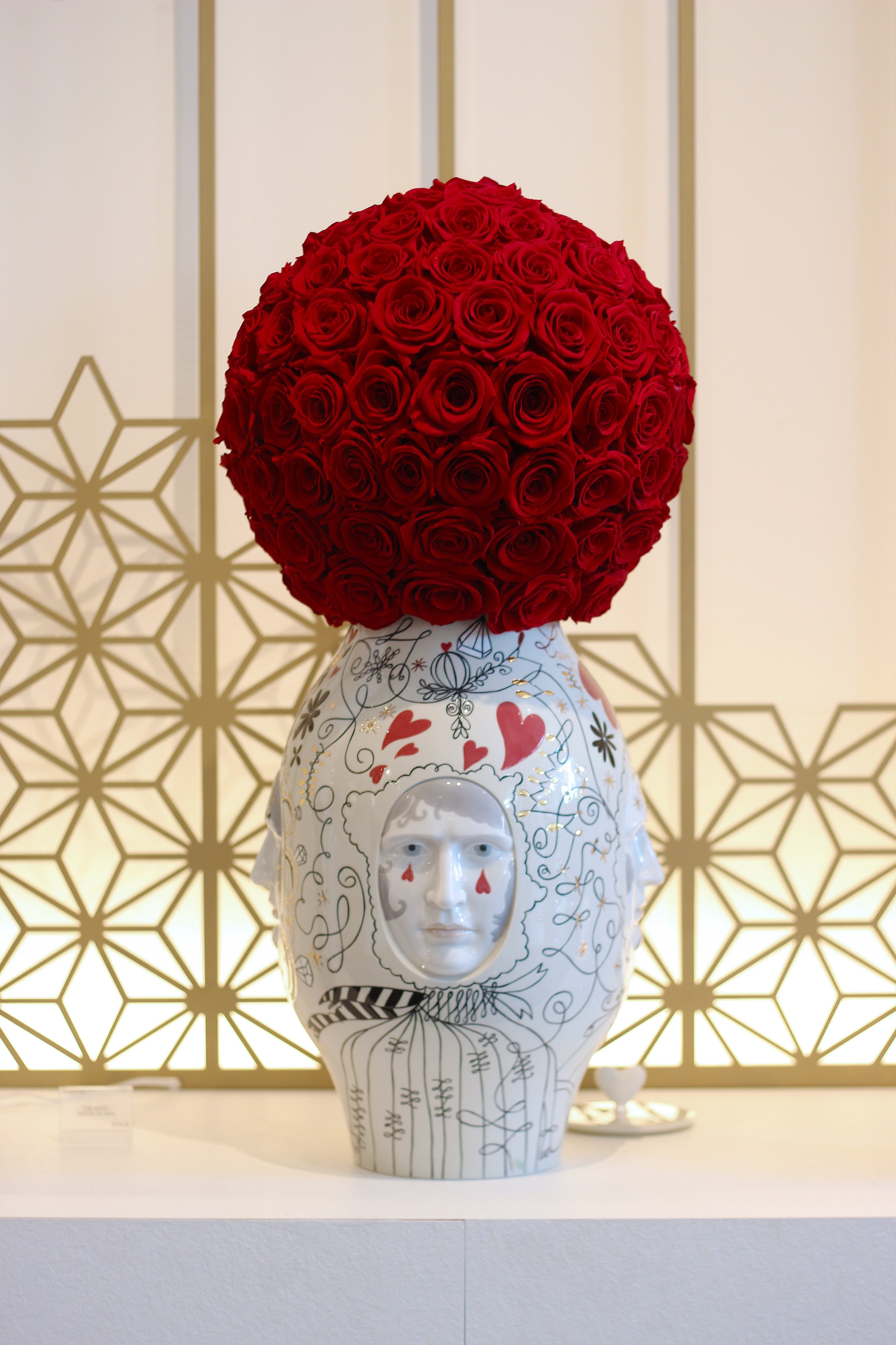 Decorative vase with red roses on a geometric patterned wall